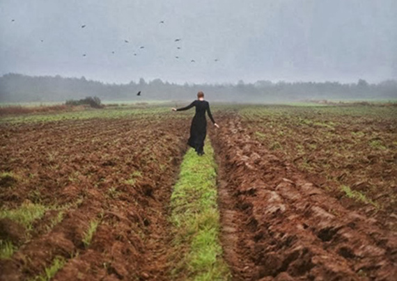 donna cammina in un grande campo arato