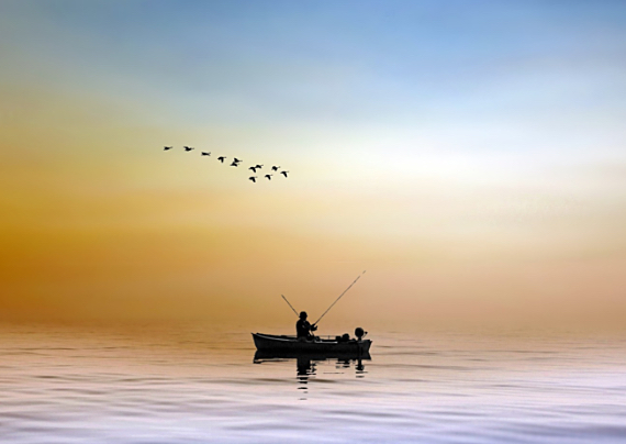 Pescatore in mare calmo al tramonto