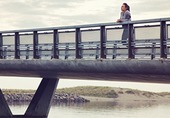 donna osserva appoggiata sopra un lungo ponte